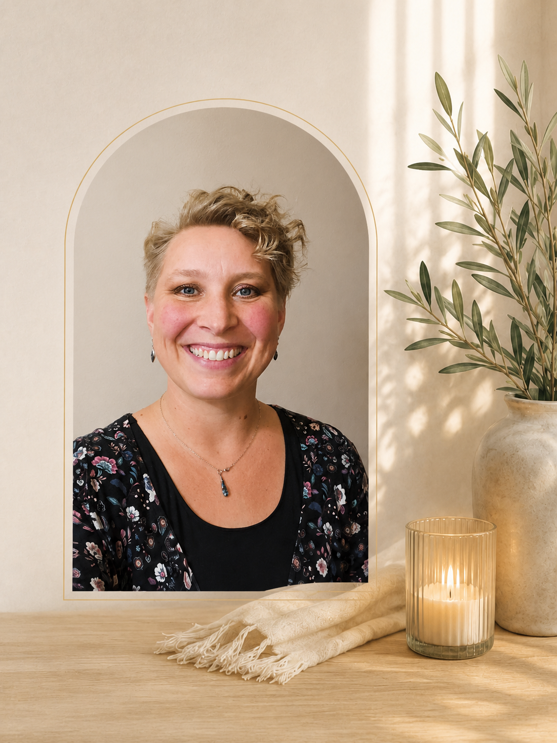 Kimberly smiling beside a vase of olive branches and a lit candle.